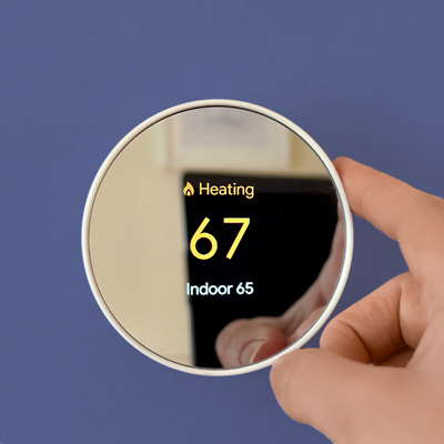 hand touching smart thermostat on wall